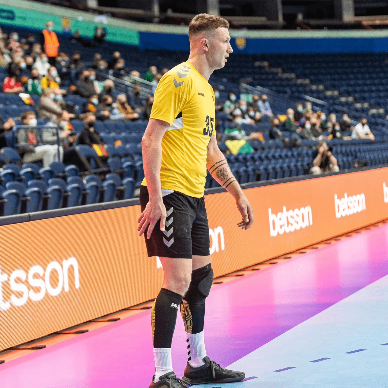 Handball player in front of orange Betsson LED perimeter board